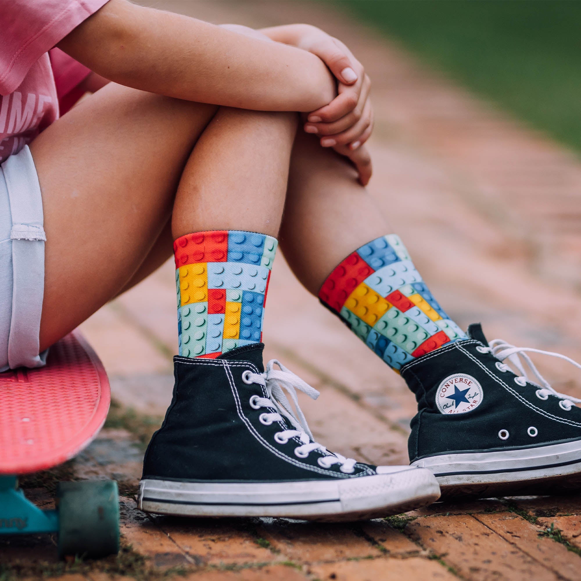 Girl sitting on Skateboard wearing Black shoes and Sox Footwear Block socks