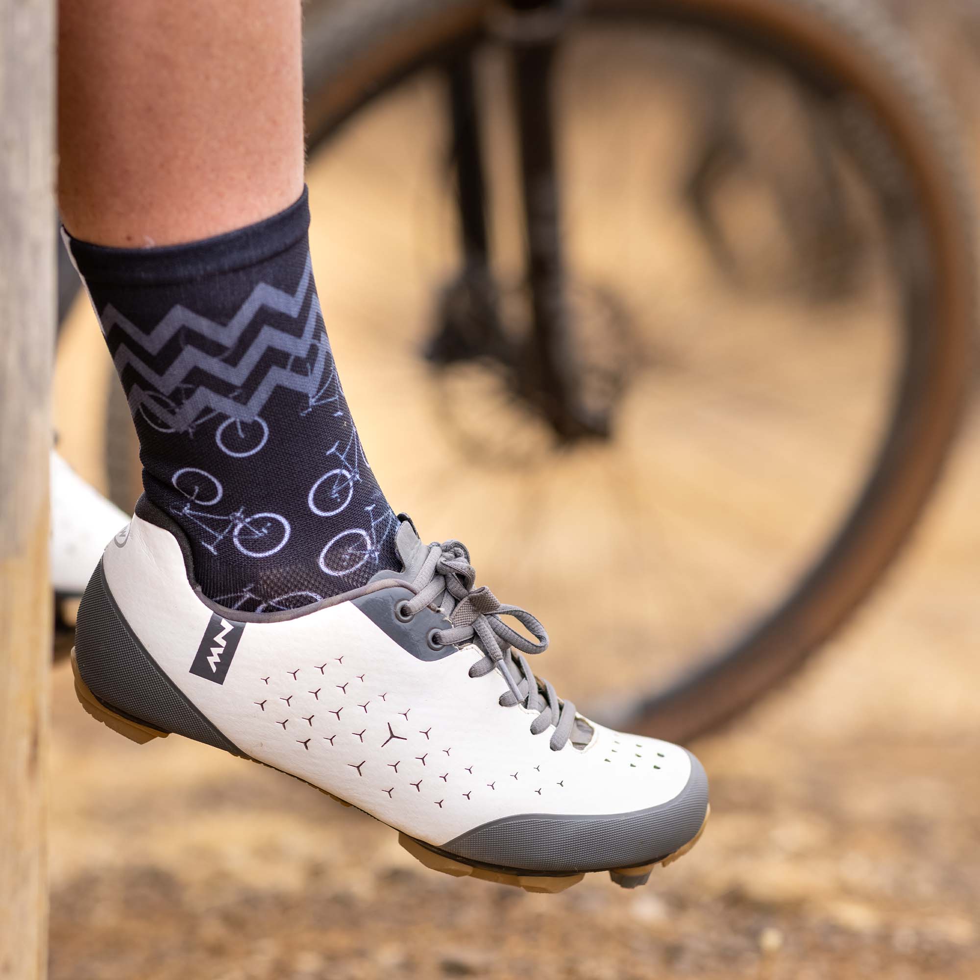 Mountain bikers foot wearing white cycling shoes and Sox Footwear Black Bikes Sock