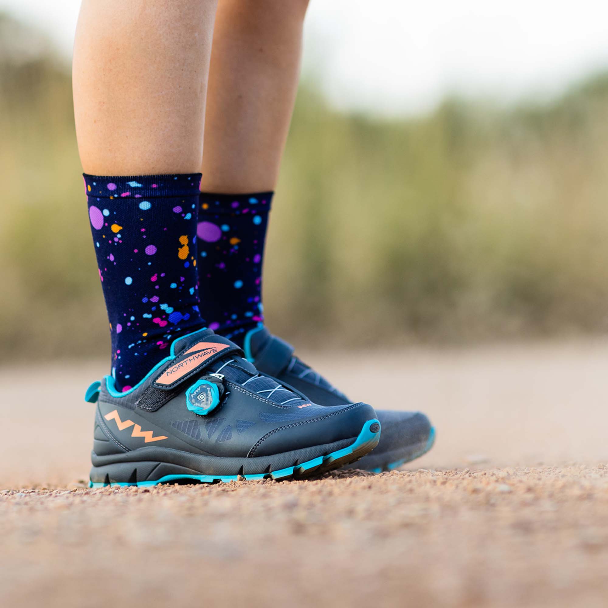 Portrait of someone's legs wearing mountain bike shoes and Purple Splash Sox Footwear.