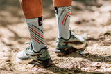 Man standing wearing performance sky socks. We are looking at the back of his calves as he faces away from us.