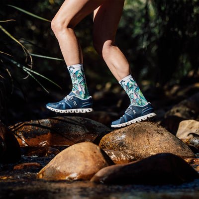 Person walking over rocks wearing brightly coloured lemur Sox Footwear